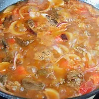 4:Return beef, add spices and hot water, then simmer covered